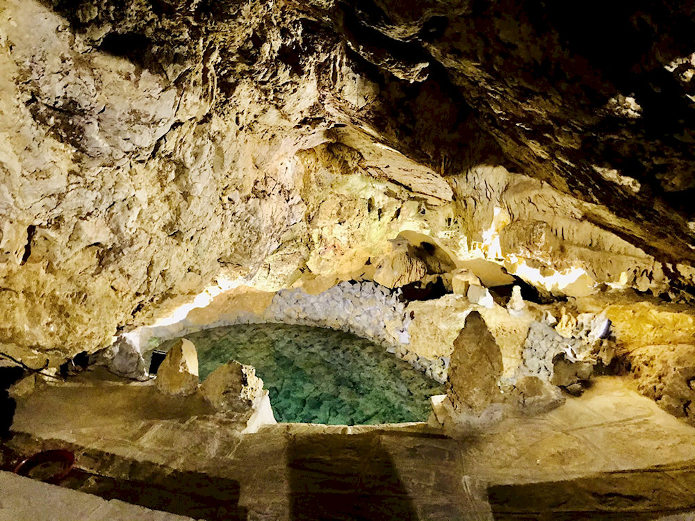 A jade-green lake embraces the cave, creating a mystical scene like a paradise on earth